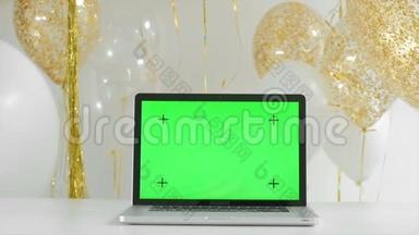 带有隔离绿色屏幕的笔记本电脑。 金色和<strong>银色气球</strong>背景。 新年概念。 1080P全高清